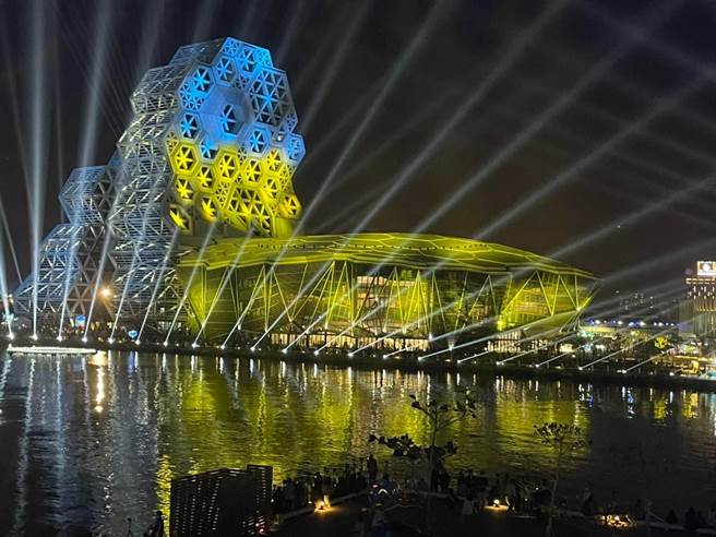 高市府力挺乌克兰，透过乌克兰国旗的蓝黄色，形成一道道光束，点亮亚洲新湾区及卫武营夜空，希望天佑乌克兰。（柯宗纬翻摄）