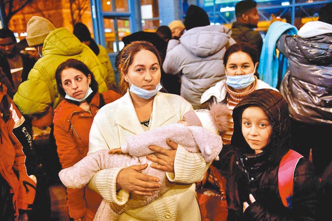 俄罗斯对乌克兰发动大规模军事行动后，一名带着孩子从乌克兰逃离的母亲站在纽加蒂车站。（路透）