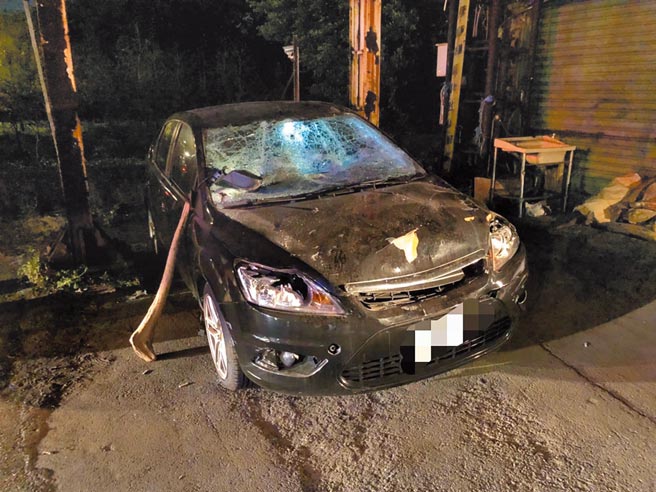 黄姓男子因事故造成车头毁损，维修费超过车辆残值，遂以砸车纾压，找来朋友持树干（副驾车门旁）砸毁玻璃以及车顶，引发警方启动快打部队近30人到场。（民眾提供／李文正台北传真）