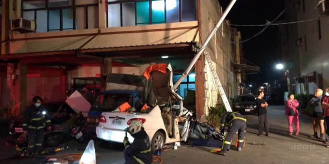 暗夜飞车衝入民宅骑楼，轿车撞到扭车变形，鹿港消防分队动用破坏器材救出女驾驶。（彰化县消防局提供／吴敏菁彰化传真）