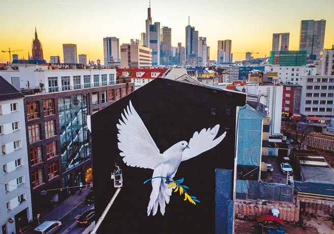 艺术家Justus Becker在德国法兰克福的房子外墙上，画了一只带有乌克兰国旗顏色树枝的和平鸽。（美联社）