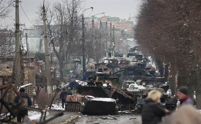 乌克兰民眾在首都基辅市郊的布查（Bucha）镇旁观烧得焦黑的俄罗斯军车。（美联社）