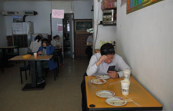 3日发生全台大停电，早餐店除了冷藏设备受影响外，继续摸黑营业，顾客用手机持续关注停电的最新消息。（张铠乙摄）