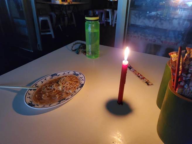 高雄光華夜市鱔魚麵店的老闆見客人上門，克難地在桌上放上蠟燭，讓客人屈就吃「燭光晚餐」。（石秀華攝）