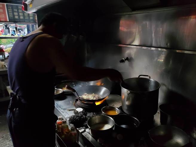 前鎮區的光華夜市上演停電後小老百姓的辛酸夜市人生，有鱔魚麵店的老闆見客人上門，硬著頭皮摸黑炒菜。（石秀華攝）