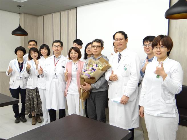 谢先生（抱花者）3年前罹急性骨髓性白血病，如今病况稳定。(曹婷婷摄)