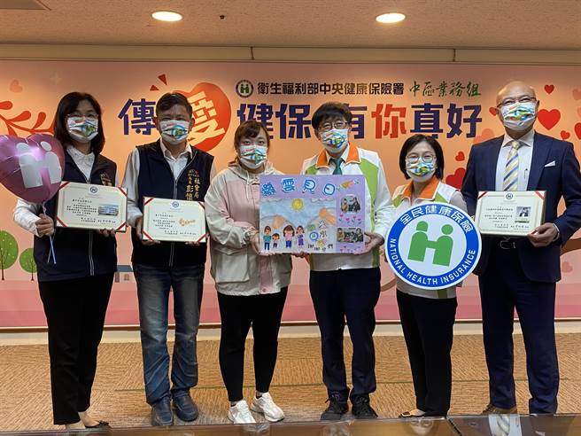 健保署中區業務組4日舉辦「傳愛健保，有你真好」活動，詹太太（左三）帶來女兒親筆繪製撥雲見日的畫作感謝健保愛心轉介，讓一家困境得以解決。（馮惠宜攝）