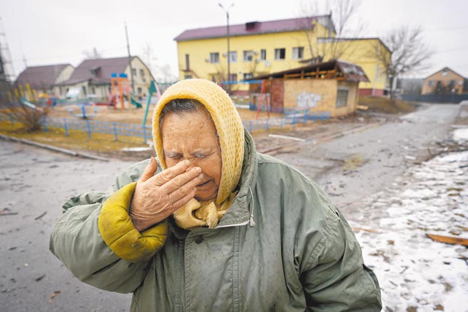 經歷俄羅斯戰機大規模空襲後，一名烏克蘭老婦人站在破碎的屋外，掩面哭泣。（美聯社）
