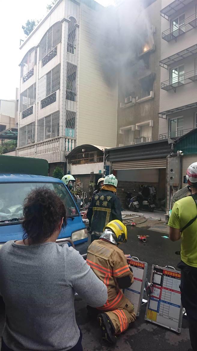 台南市南区民宅起火，屋主苏太太（灰衣者）站在门外看着自家火势仍燃烧，惊魂未定。（程炳璋摄）