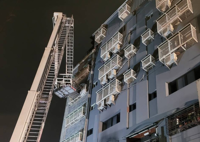 台中市兴中街6日发生大火，抢救过程中有三名受困民眾站在高楼层外的窗台，其中一人坠落，幸有路旁轿车缓衝，送医后无生命危险，另外2人由云梯车救下，消防队一共在火场救出8人，其中一名六十五岁妇人在今晚六点多被找到时因躲在三楼浴室中，已无生命迹象。（陈界良摄）