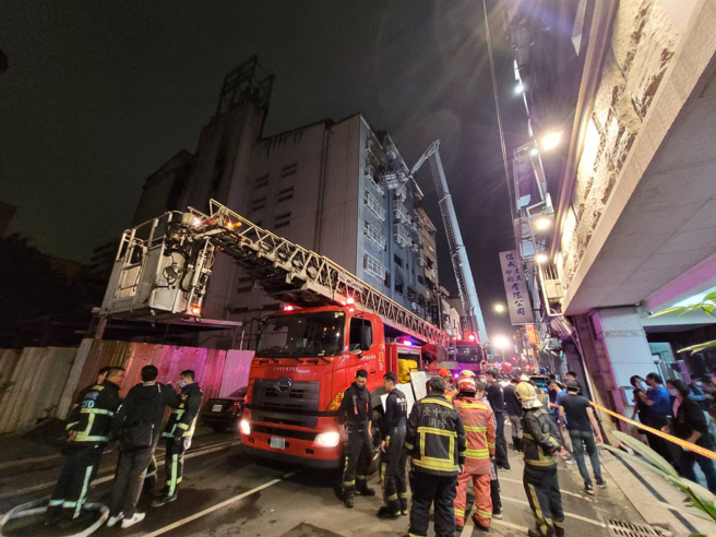 台中市兴中街6日发生大火，抢救过程中有三名受困民眾站在高楼层外的窗台，其中一人坠落，幸有路旁轿车缓衝，送医后无生命危险，另外2人由云梯车救下，消防队一共在火场救出8人，其中一名六十五岁妇人在今晚六点多被找到时因躲在三楼浴室中，已无生命迹象。（陈界良摄）