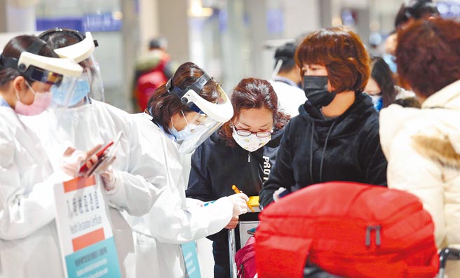 中央流行疫情指挥中心5日公布国内新增80例新冠肺炎病例，分别为8例本土个案及72例境外移入。图为桃园机场第二航厦，刚下机的旅客排队查验入境检疫凭证。（范扬光摄）