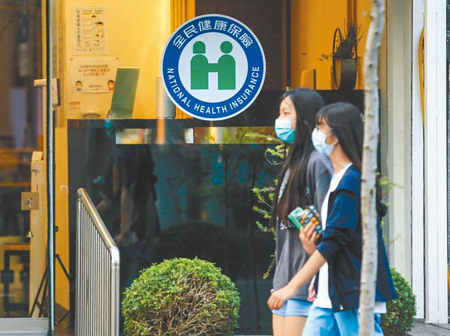 健保給付未來不再侷限於醫療院所，將擴及公共衛生、預防醫學，相關給付規定近日將在健保共擬會議中討論，若一切順利，有望在上半年上路。圖為兩位女學生路過一間健保診所。（粘耿豪攝）