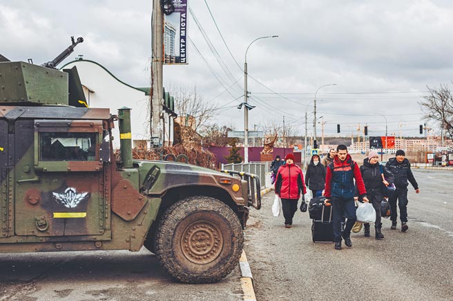 乌克兰首都基辅的周边城市，连日遭受到俄军的猛烈炮击，一批民眾4日透过基辅附近伊尔平市撤离，行经街头的军车。（新华社）