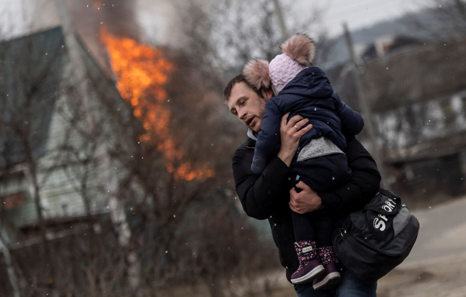 俄军猛烈炮击基辅西郊的伊尔平（Irpin），1名乌克兰男子3月6日抱着小孩逃离当地。（路透）