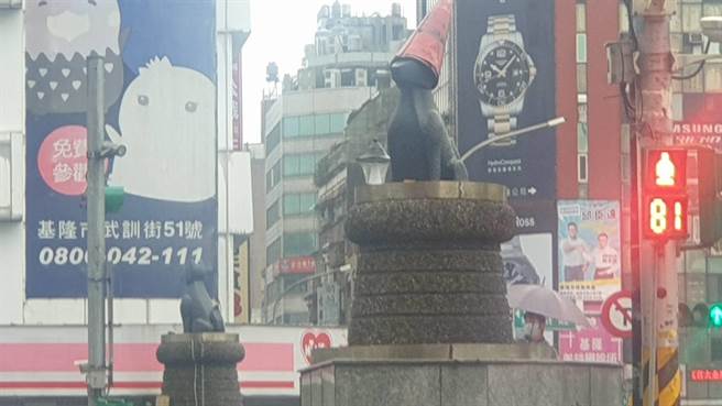 田寮河富狗桥出现奇异现象，有市民眼尖发现，狗雕像头上多了反光锥，如同戴上雨帽，引起路过民眾关注。（陈彩玲摄）