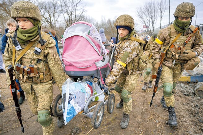 烏克蘭軍人5日在俄羅斯空襲後，協助民眾逃離烏克蘭伊爾平鎮，2名士兵正提著嬰兒車。（美聯社）