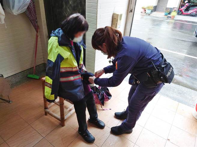 高雄市卢姓老妇人在寒天里迷途，全身被雨淋湿在骑楼受冻，女警陈家蓁获报到场，将身上警察雨衣脱下替老妇人穿上。（翻摄照片／石秀华高雄传真）