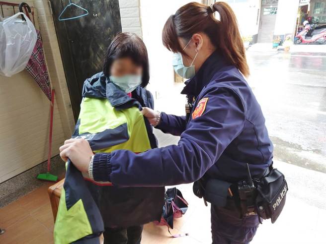 女警陈家蓁细心地帮迷途的卢姓老妇人穿上警察雨衣御寒。（翻摄照片／石秀华高雄传真）