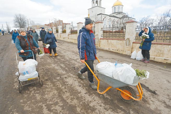 圖為3月6日，在頓涅茨克的一個村莊，當地居民領取人道主義援助物資。（新華社）