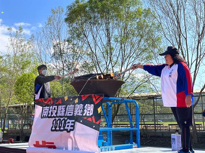 望鄉部落資深神力女力士全阿喜（右）及地利排球常勝軍主攻手幸偉祥（左）手持聖火點燃聖火台。（公所提供／吳建輝南投傳真）