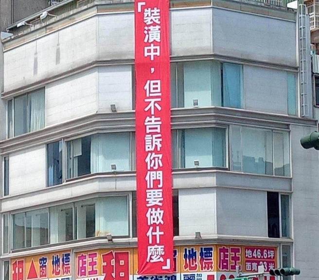 高雄市中山一路、六合路一间5楼高的黄金三角窗店面，从2020年中开始在外墙悬挂红色大布条，写着「装潢中，但不告诉你们要做什么」，令人摸不着头绪。（柯宗纬翻摄）