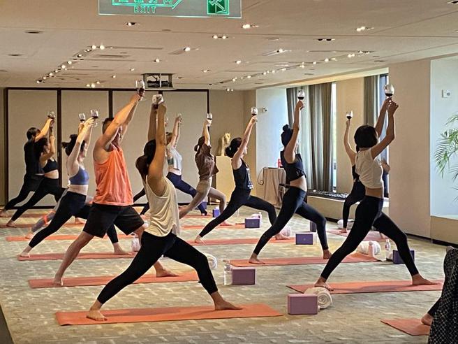 （争取女性消费，台北君悦酒店携手全真瑜珈携手推出「红酒瑜珈」课程。图／台北君悦酒店提供）