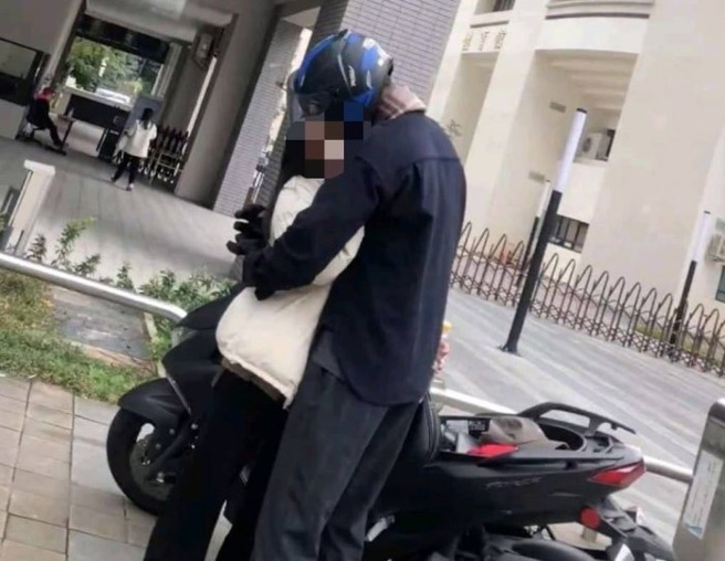 小情侶在某大學人行道上熱吻，其一旁機車遭拍照舉發，舉發照片一出，引起網友笑稱「為愛破財」（翻攝自Dcard）
