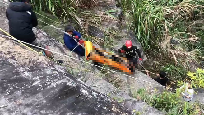 苗栗县南庄乡鹿场部落神仙谷11日下午发生 2名摄影师坠潭溺毙意外，救难人员以人力将落潭者搬运上方坡地。（资料照/读者提供）
