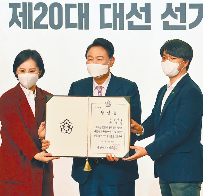 韩国总统当选人尹锡悦（中）在韩国首尔国会图书馆举行的总统选举营解散仪式上，展示总统选举证书。（美联社）