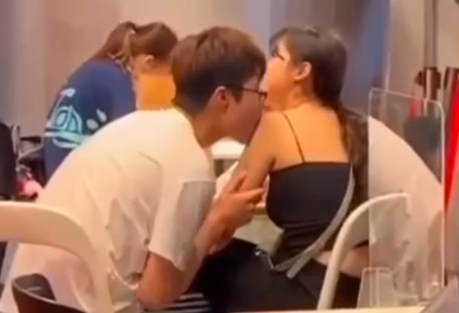 1对情侣在餐厅展现惊人的亲密行为，男方先是朝女方手臂猛亲，接着又大口含住女方肩膀，疑似还有「舔」的动作，最后男方才将嘴凑到女方嘴边接吻起来。（翻摄自脸书「爆废公社」）