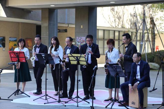 （友达光电董事长彭双浪（右4）等人，13日在东海大学「花舞再现画展音乐会」现场，演奏萨克斯风的场景。图／东海大学提供）