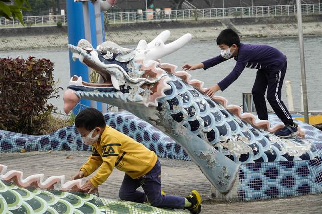 台北剑潭三脚渡码头边的龙舟公园有龙形水泥造景，两名儿童骑在龙头上嬉戏拍照。（黄子明摄）