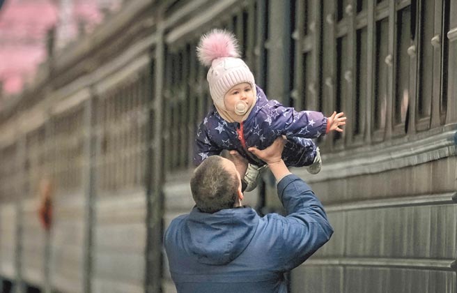俄乌战事持续，12日在基辅，一名男子送女婴上火车撤离。（美联社）