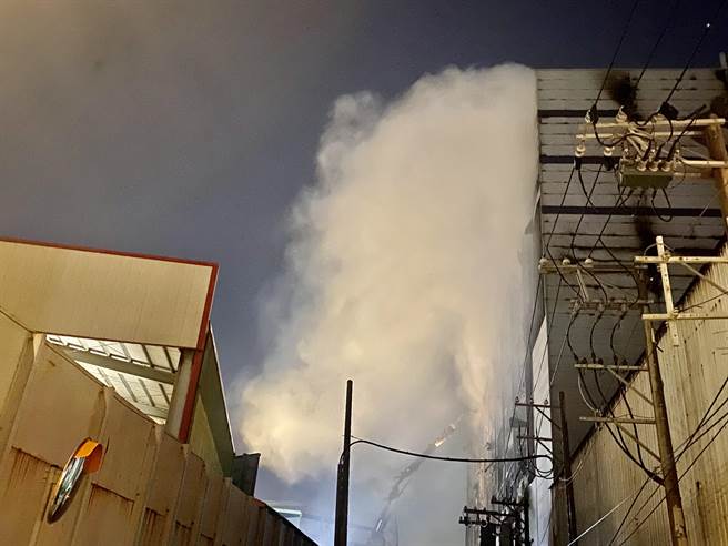 桃园市芦竹区美福仓储10日大火后持续闷烧，消防局正进行残火处理，晚间有大量浓烟冒出。（陈梦茹摄）