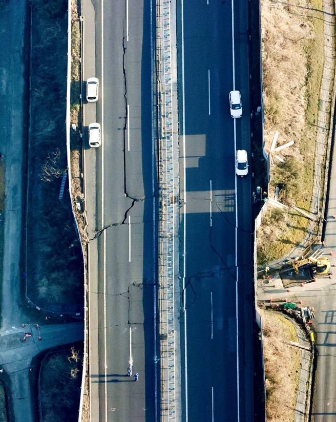 日本东北7.4强震造成白石市一座高速公路路面出现巨大裂缝。（图／路透社、共同社）