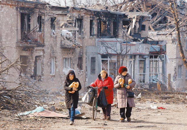 俄乌战火衝突持续，遭受飞弹攻击的乌东地区，街道残破如废墟，图为接受人道援助的当地民眾。（路透）