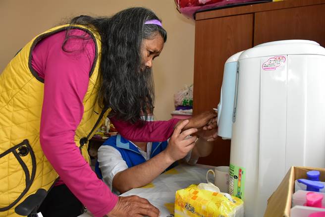 游姓妇人（左）学习使用新的开饮机。（新竹县政府提供／罗浚滨新竹传真）