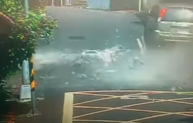 路口监视器拍下惊悚一瞬间，只见1辆白车刚驶离大楼，外墙就应声倒塌，掀起惊人粉尘，更直接覆盖停在路变的轿车。（警方提供）