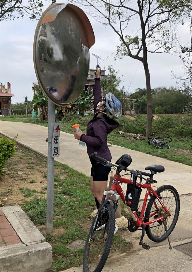 个子不高的陈姵君伸直手脚，太高的镜面只能刷上一半，却让路过的乡亲看到洋溢爱心、热情的完整身影。（李金生摄）