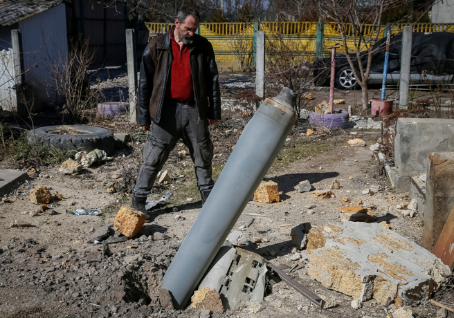 一名住在基辅北部前线的乌克兰人3月17日看着炸了自家住宅的俄军火箭弹残骸。（路透）