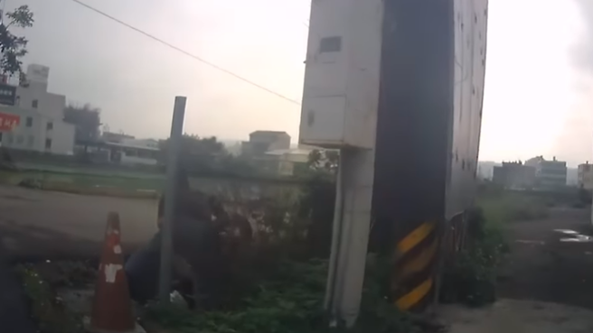 骑士载着女友在路口准备违规闯红灯右转进巷子，没想到巷子突然衝出1辆轿车发生擦撞，骑士当场向右边自摔、整辆车甚至翻转180度「掉入水沟内」。（翻摄自脸书「记者爆料网」）