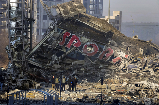 俄軍猛轟烏克蘭首都基輔，幾乎把一座購物中心夷為平地，圖為民眾21日在現場看著遭摧毀的購物中心。（美聯社）