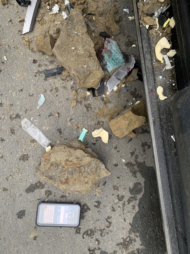休旅車被落石砸破擋風玻璃，駕駛當場開放性骨折；事故照中，休旅車玻璃破出驚悚大洞，一旁的車身零件還有血跡。（翻攝照片）