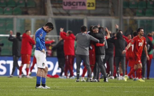義大利主場落敗，後衛佛羅倫齊悵然若失的站在場中，與後方慶祝勝利的北馬其頓球員形成強烈對比。（路透）