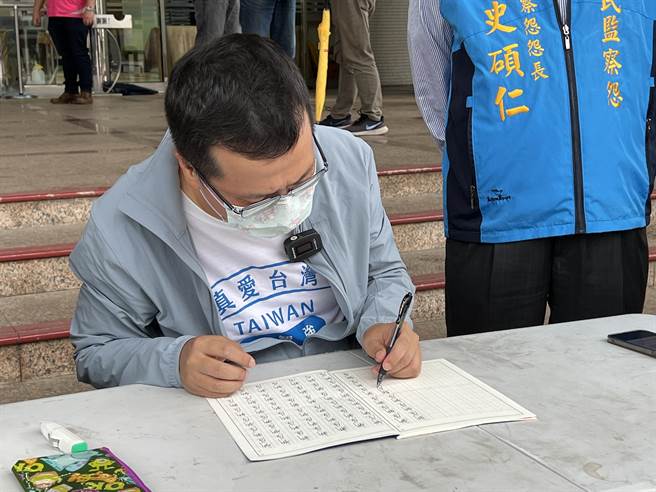 台北市议员罗智强因被桃园市长郑文灿点名错把「新屋」写成「新乌」，26日带着特制小学生生字簿赴桃市府前罚写千遍，写到手酸一度改用左手罚写。(蔡依珍摄)