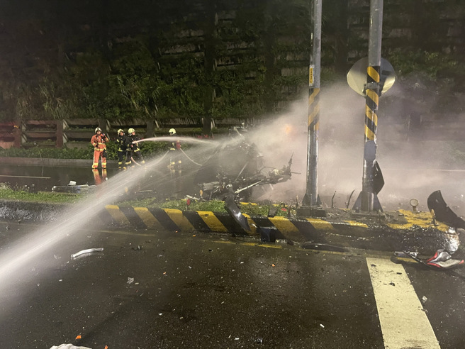 國道3號北上深坑匝道口27日凌晨一輛特斯拉自撞分隔島起火燃燒，消防隊到場撒下大量水柱滅火。（葉書宏翻攝）