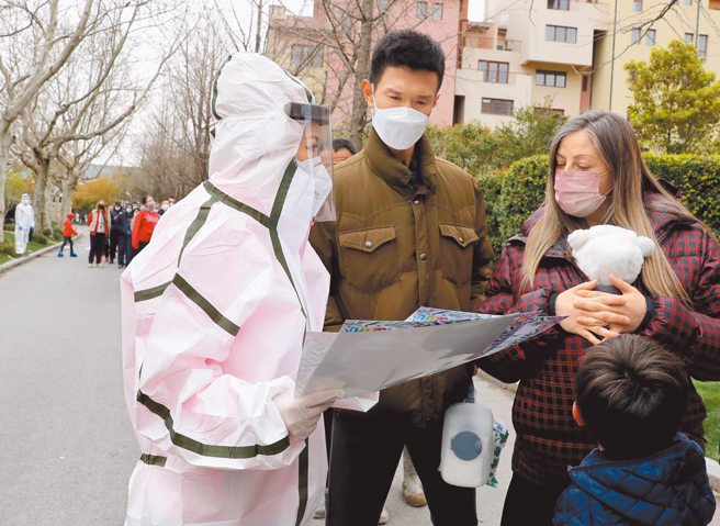 上海明起「分批封控普篩」住宅社區實施封閉式管理。圖為上海防疫人員向民眾說明社區封控規定。（新華社）