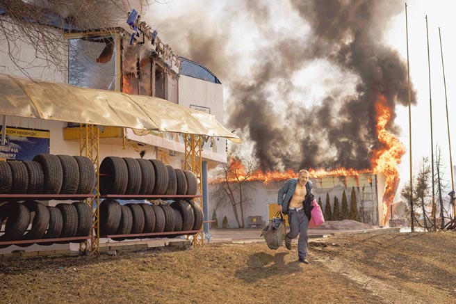 乌克兰东部城市哈尔科夫持续遭受俄罗斯轰炸，据称该市150万居民已有约1/3逃离家园。图为哈尔科夫一名男子从遇袭起火的商店中抢救出东西。（美联社）