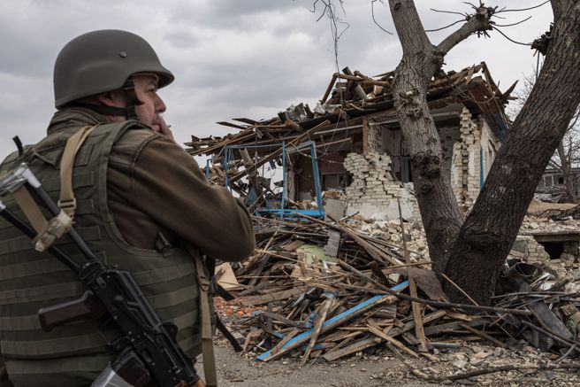 俄军持续侵略乌克兰，1名乌军26日站在被摧毁的民宅前。（路透）